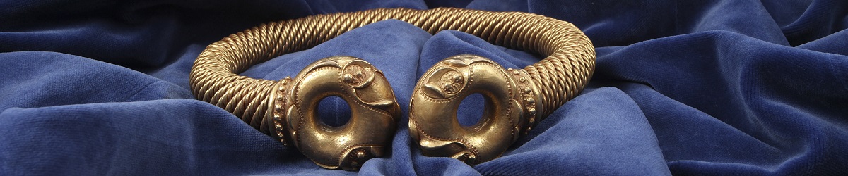The Newark Torc on a blue velvet cloth. The Torc is an elaborate iron age necklace made from twisted gold wire.
